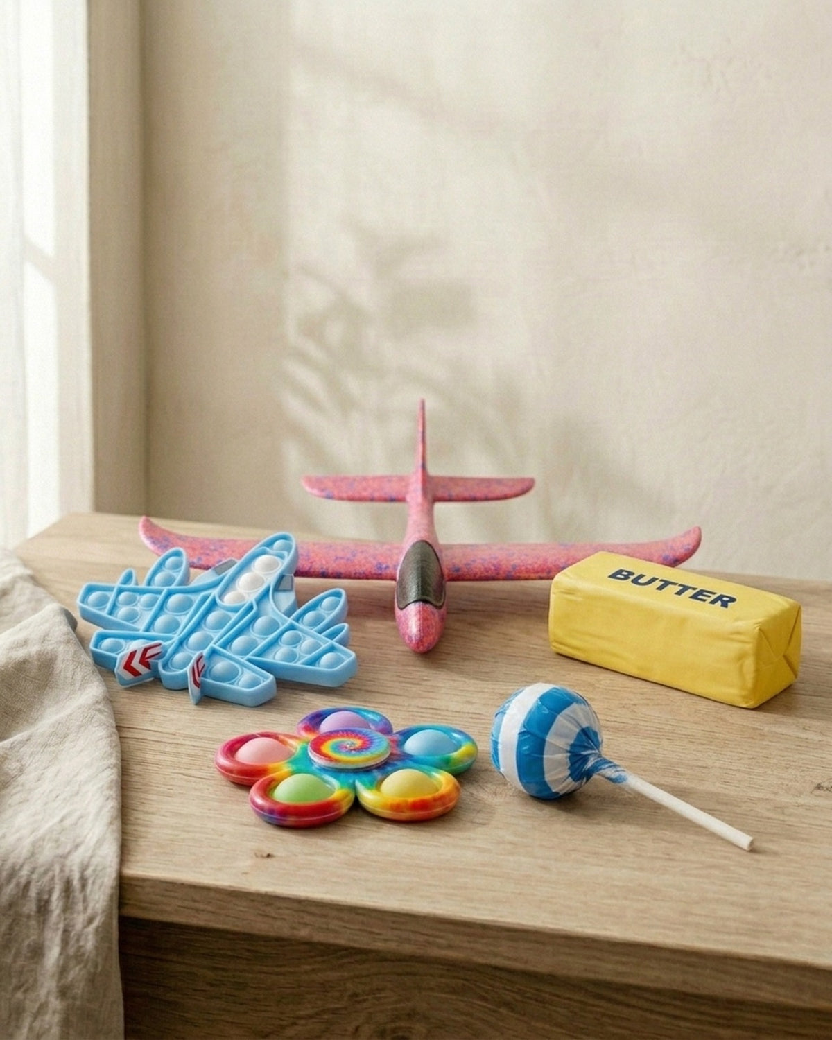 Everything that comes in the Soft Cotton and Water-Resistant bags: the foam glider, aeroplane pop it, tie-dye spinner, butter squishy and sugar-free lollipop (the card and lanyard not shown)