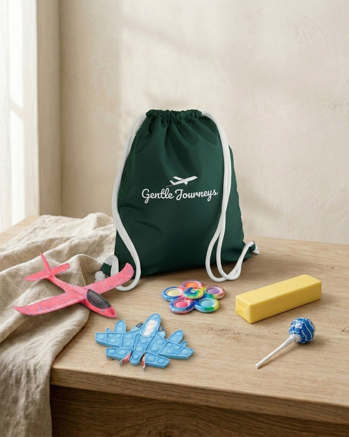 Green Water-Resistant sensory travel bag with the foam glider, aeroplane pop it, tie-dye spinner, butter squishy and sugar-free lollipop