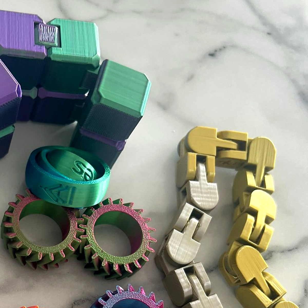 Gentle Journeys fidget toys, including a 3D printed infinity cube, spinning ring, linked chain and gear fidgets in pearlescent PLA